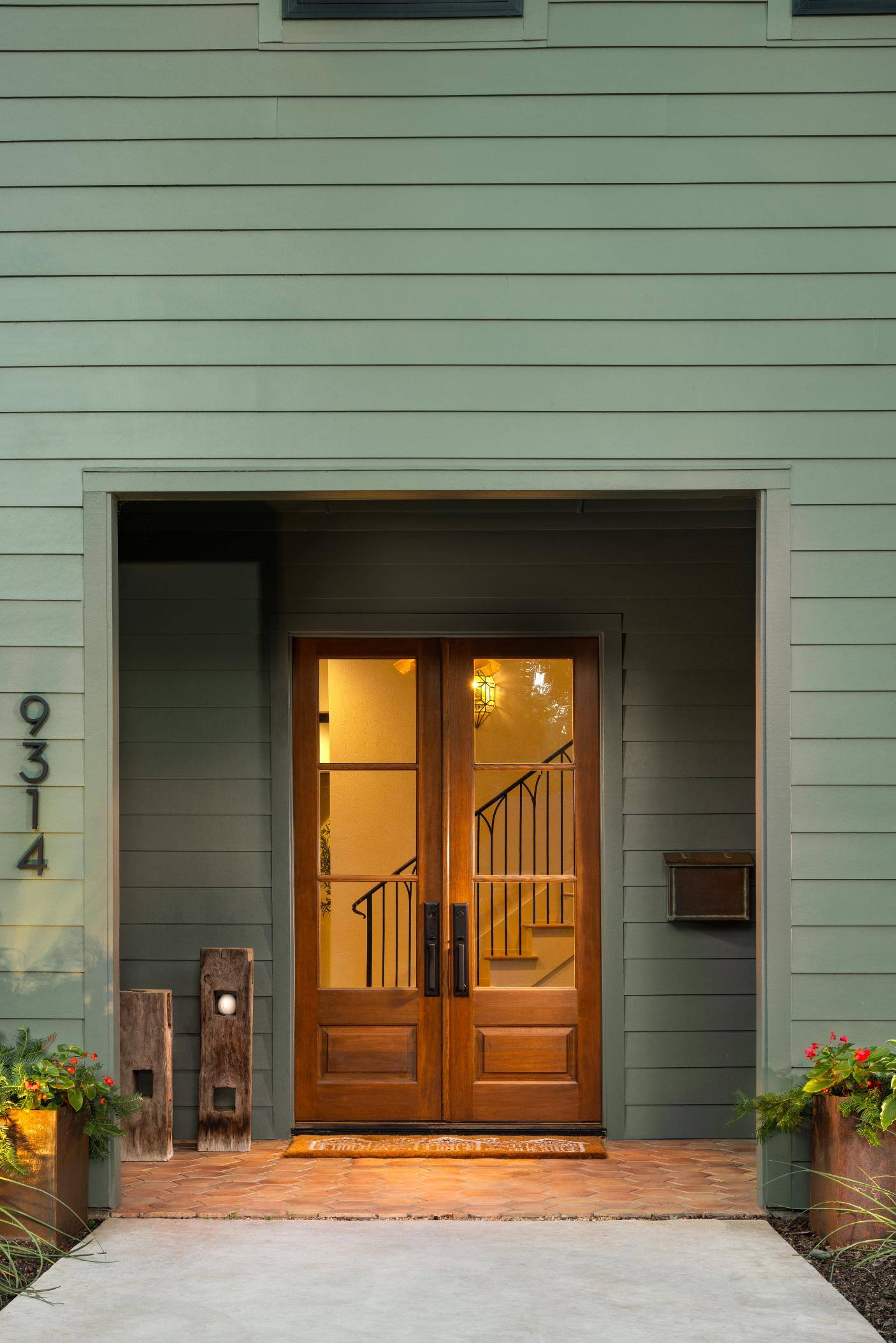 Front entrance of a green-sided home with wooden double doors, custom home by Sardone  McClain in Dallas, Texas