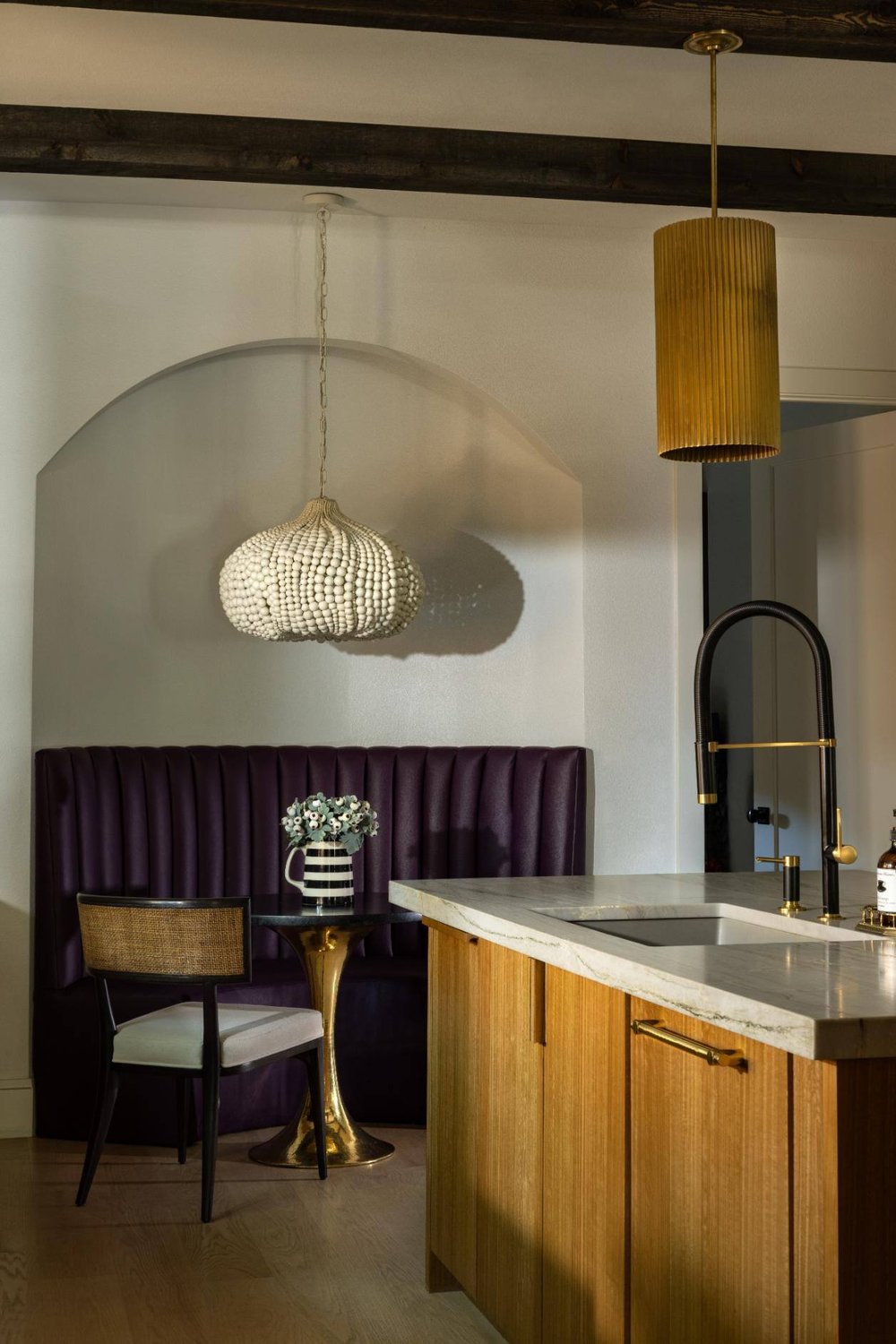 Intimate dining nook in a kitchen with a purple upholstered booth and modern lighting, custom home by Sardone  McClain in Dallas, Texas