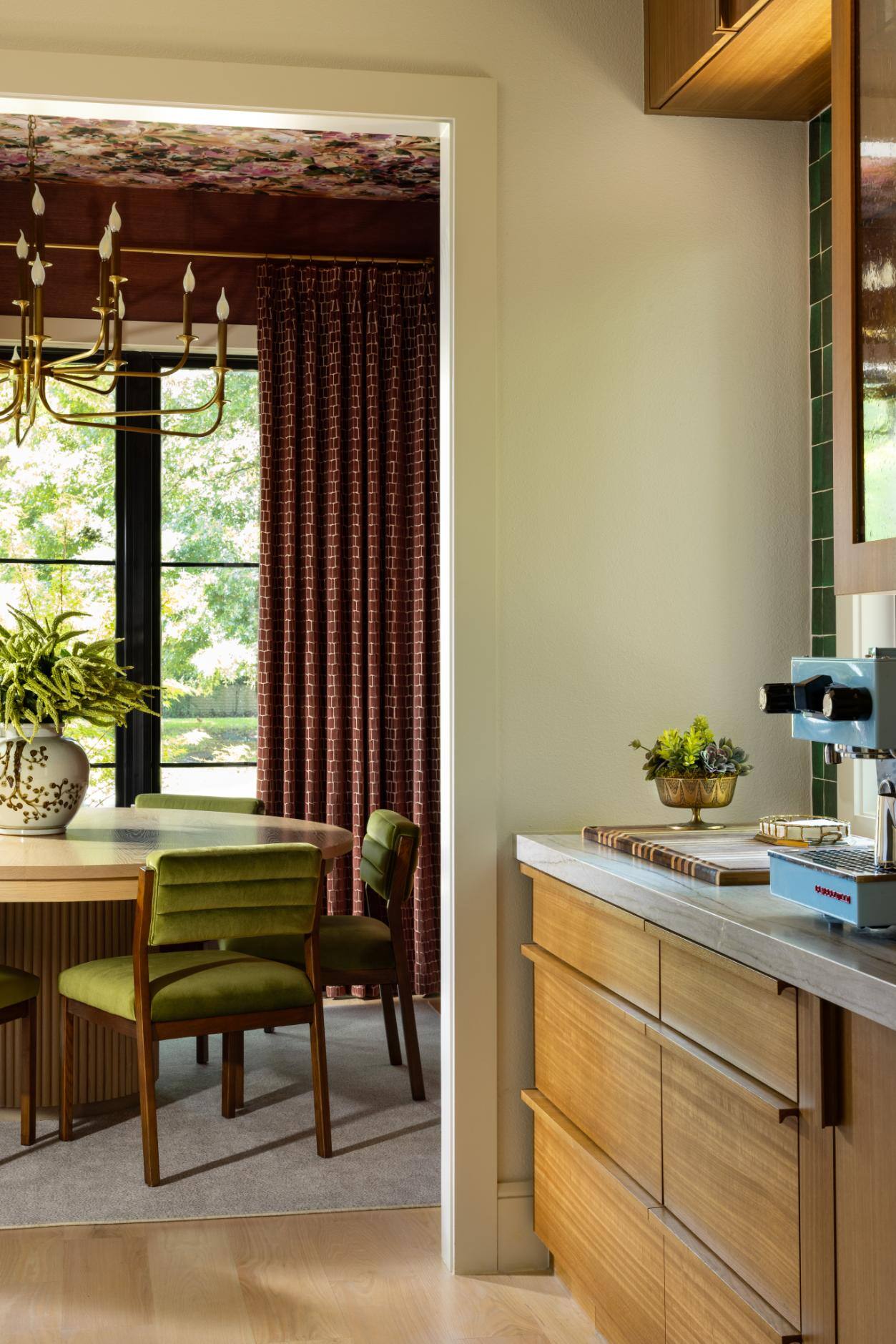 View of a modern dining room with green chairs and red curtains in a custom home by Sardone McClain in Dallas, Texas