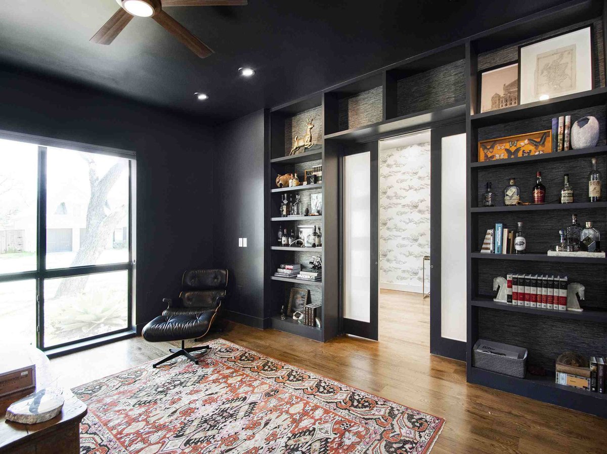 Black painted walls in luxury home remodel with sliding doors opened in between built-in open shelving by Sardone | McLain