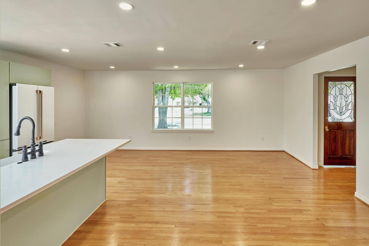 Open-concept kitchen remodel with white countertops and large island in Sardone | McLain remodel in Dallas, TX