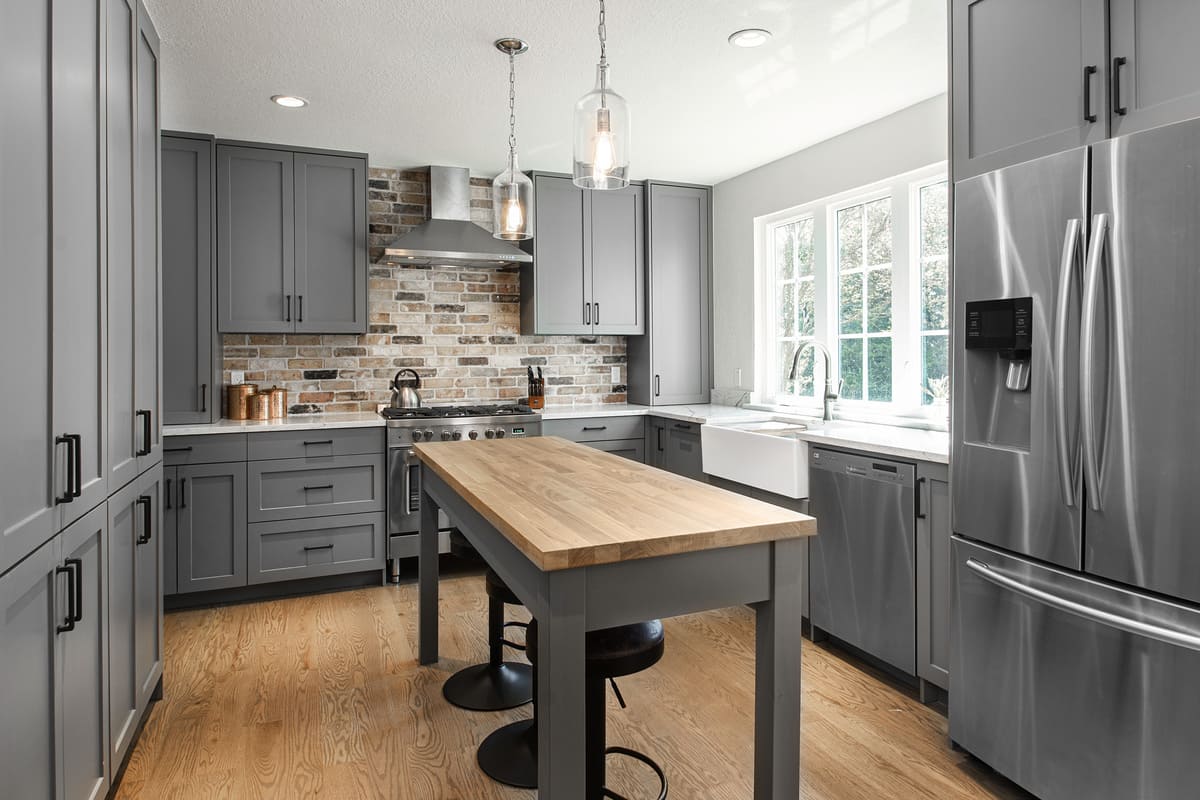 Gray shaker-style cabinets and island with seating in U-shaped Dallas kitchen remodel by Sardone | McLain