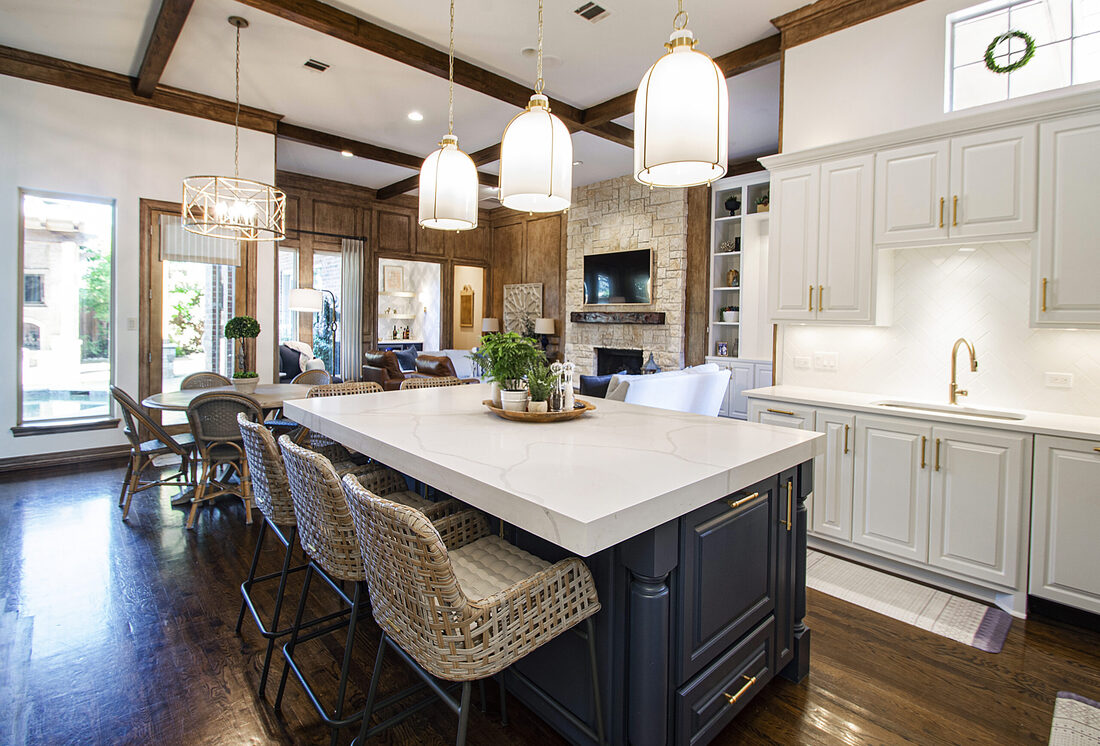 Three pendant lights above kitchen island with seating hanging from coffered ceiling with wood beams