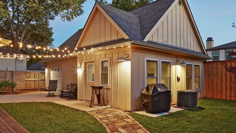 Remodeled guesthouse exterior at dusk with stone pathway to patio