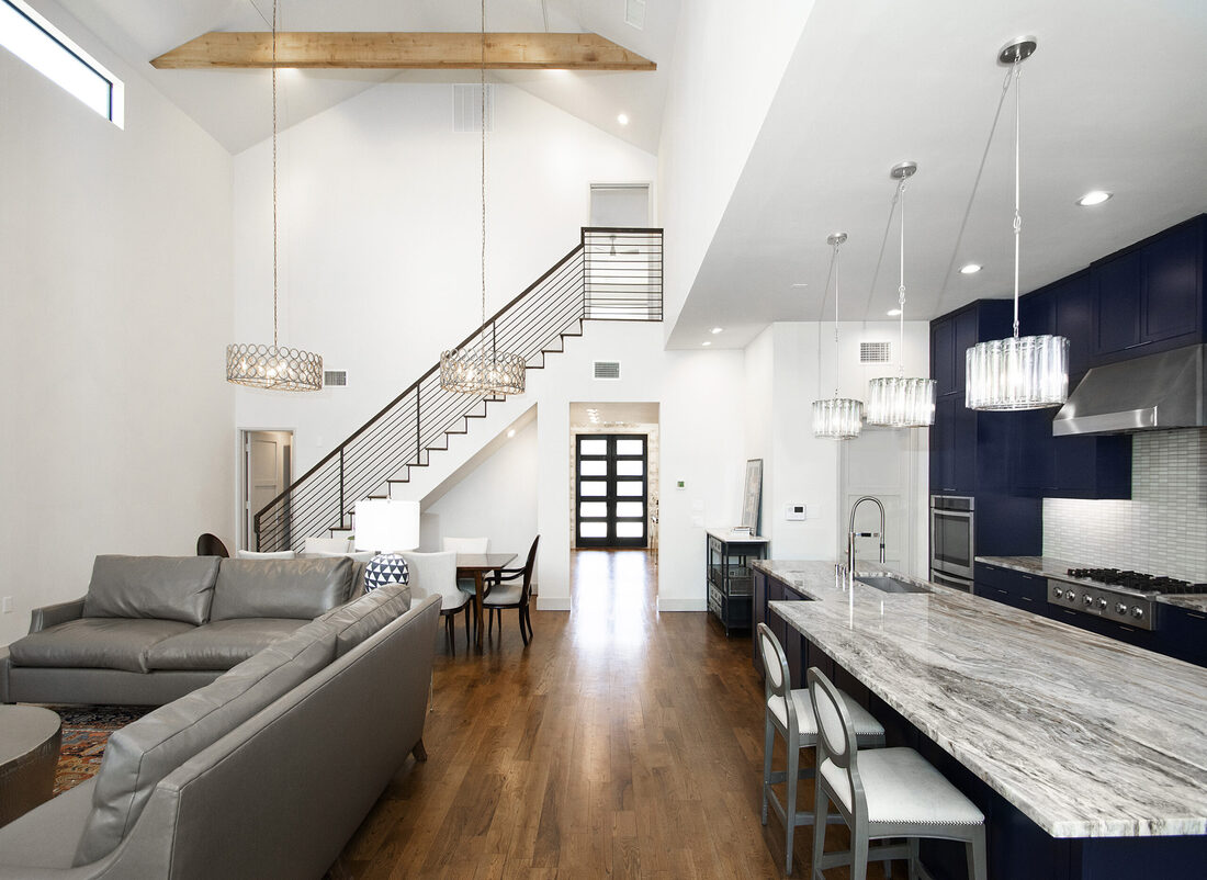 Open-concept first-floor of Dallas, TX home interior with vaulted ceilings and modern light pendants