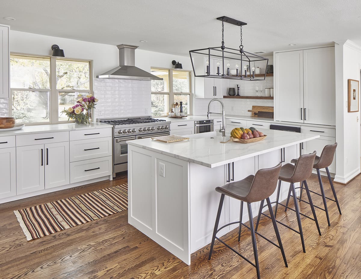 Three bar stools at island with storage in white kitchen remodel by Sardone | McLain in Dallas, TX